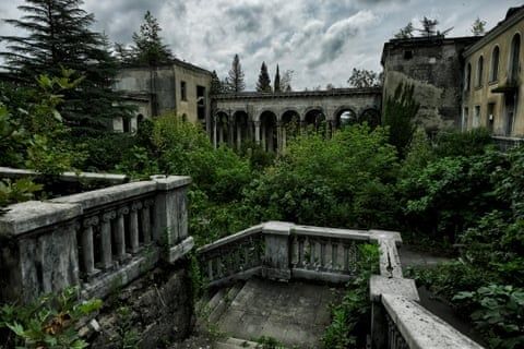 Verwachsene Ruinen mit steinernen Balustraden und Arkadengang unter Wolkenhimmel