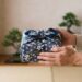 Hände reichen ein traditionell gemustertes, verpacktes Geschenk