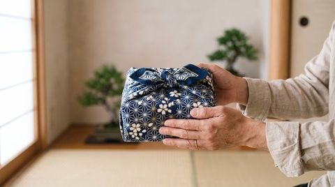 Hände reichen ein traditionell gemustertes, verpacktes Geschenk